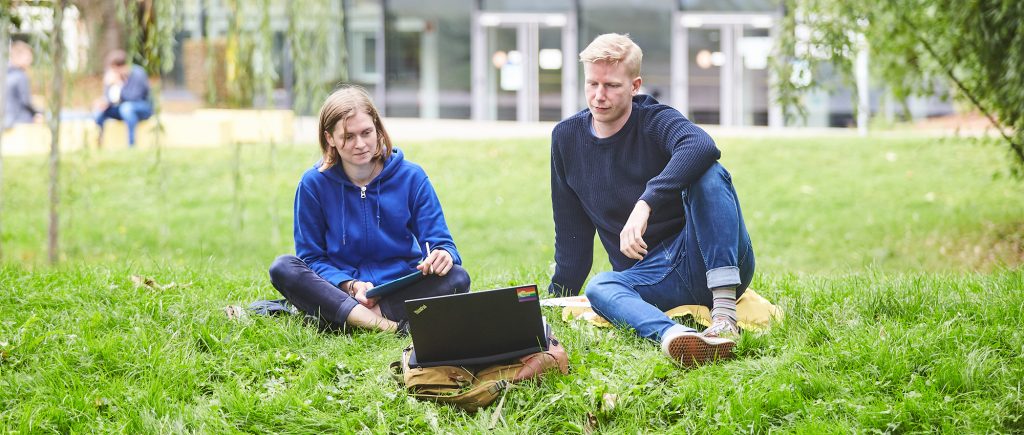 Studierende mit Laptop im Grünen
